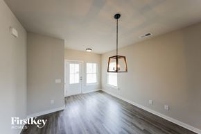 Cullman house for rent - A well-lit, empty room with a wooden floor and a hanging light fixture.