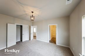 Cullman house for rent - A spacious room with a light fixture hanging from the ceiling and a carpeted floor.