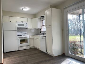 Hartville apartment for rent - A kitchen with white appliances and cabinets with a view of trees outside.