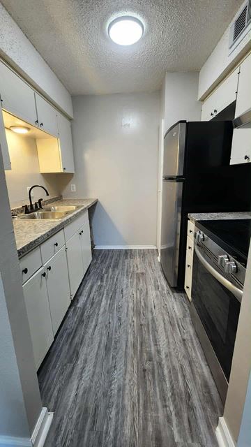Killeen apartment for rent - A kitchen with a black refrigerator and stove top oven.