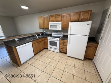 Durant apartment for rent - A kitchen with white appliances and wooden cabinets.