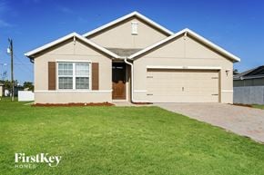 Cape Coral house for rent - a beige house with a lawn in front of it