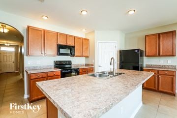 Cape Coral house for rent - a kitchen with wooden cabinets and a granite counter top