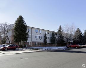Aurora apartment for rent - A red car is parked in front of a white building with a tree in front of it.