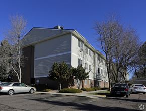 Aurora apartment for rent - A silver car is parked in front of a grey building.