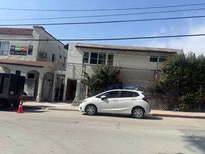 Los Angeles apartment for rent - A white car is parked in front of a building with a phone number on it.