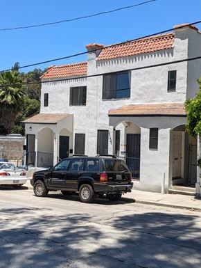 Los Angeles apartment for rent - A black car is parked in front of a white building with a red tile roof.