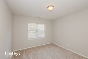 Charlotte house for rent - a spacious bedroom with a large window and carpeted flooring
