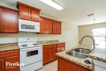 Cape Coral house for rent - A kitchen with brown cabinets and a white stove top oven.