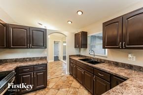 Lehigh Acres house for rent - a kitchen with dark cabinets and granite counter tops and a sink