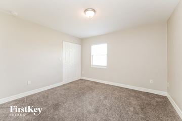 Lehigh Acres house for rent - the spacious living room with carpet and a door to the bedroom