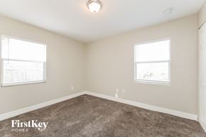 Lehigh Acres house for rent - a bedroom with a carpeted floor and two windows