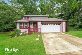 Lewisville house for rent - A red and white house with a garage is surrounded by greenery.