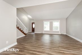 Lewisville house for rent - A spacious room with wooden floors and a staircase leading to another level.