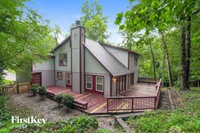 Lewisville house for rent - A house with a red deck is surrounded by trees.