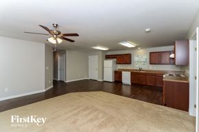 Douglasville house for rent - an empty living room and kitchen with a ceiling fan
