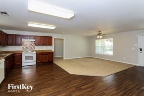 Douglasville house for rent - an empty kitchen and living room with wood flooring and a rug
