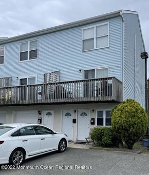 Keansburg apartment for rent - A white car is parked in front of a blue building.