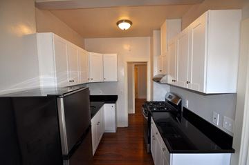 Oakland apartment for rent - a kitchen with black counter tops and white cabinets