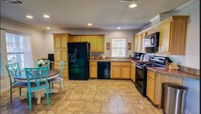 Duson house for rent - a kitchen with a dining table and a black refrigerator