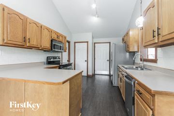 Pittsboro house for rent - a kitchen with wooden cabinets and a white counter top and a sink