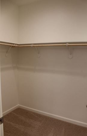 Merced house for rent - A white wall with a brown carpet and a coat rack.