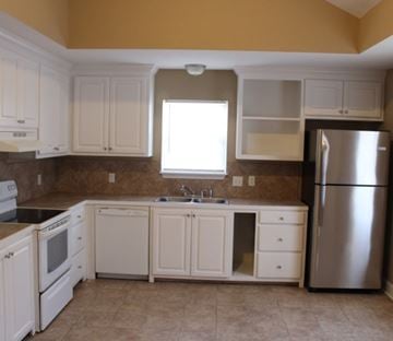 Hattiesburg house for rent - A kitchen with white cabinets and a stainless steel refrigerator.