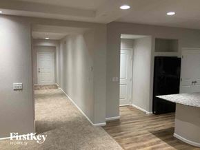 Fountain house for rent - A spacious room with a carpeted floor and a kitchen area with a black fridge.