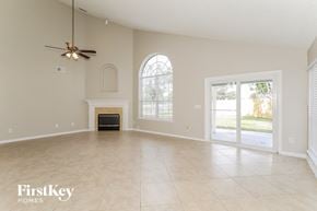 Orange Park house for rent - A spacious room with a fireplace and a ceiling fan.