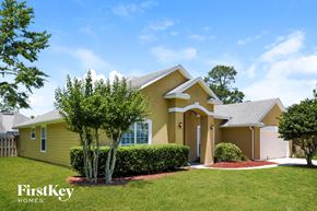 Fleming Island house for rent - a yellow house with a lawn and trees