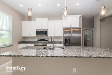 Lehigh Acres house for rent - a kitchen with white cabinets and granite counter tops