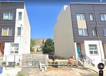 Philadelphia house for rent - A construction site is in the foreground with workers and construction materials.