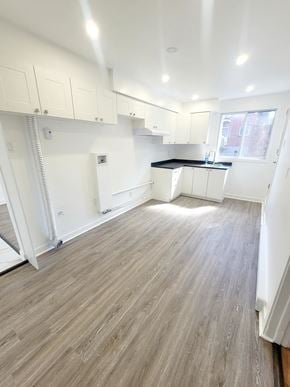Montréal apartment for rent - an empty kitchen with white cabinets and a wood floor