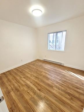 Montréal apartment for rent - an empty living room with wood flooring and a window