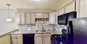 Fort Worth apartment for rent - a kitchen with white cabinets and black appliances