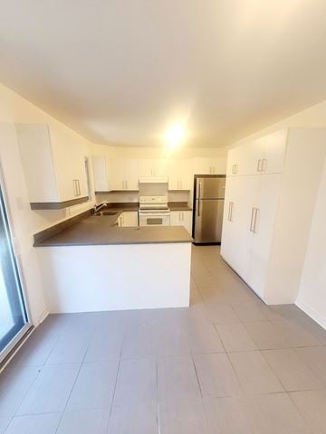Saint-Laurent apartment for rent - A kitchen with white cabinets and a stainless steel counter.