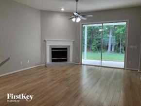 St Johns house for rent - an empty living room with a fireplace and a ceiling fan
