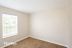 Indianapolis house for rent - a bedroom with a large window and brown carpet