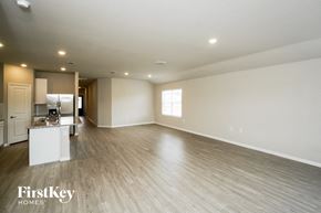 San Antonio house for rent - an empty living room and kitchen with wood flooring and white walls