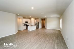 San Antonio house for rent - an empty living room and kitchen with wood flooring and white walls