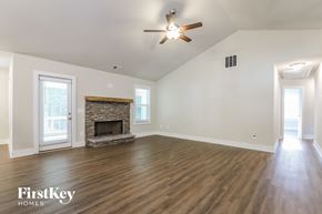 Gainesville house for rent - A spacious room with a fireplace and wooden flooring.