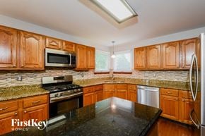 O Fallon house for rent - a kitchen with wooden cabinets and granite counter tops and stainless steel appliances
