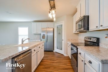 St Augustine house for rent - a kitchen with white cabinets and stainless steel appliances and marble counter tops