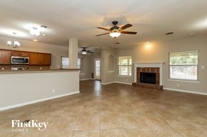 Cibolo house for rent - A spacious living room with a fireplace and a ceiling fan.