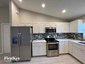 Cape Coral house for rent - a kitchen with stainless steel appliances and white cabinets