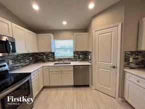 Cape Coral house for rent - a kitchen with white cabinets and a sink