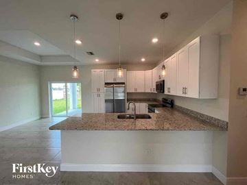 Cape Coral house for rent - a kitchen with white cabinets and a granite counter top