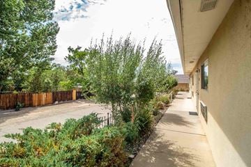 Farmington apartment for rent - an empty sidewalk next to a building with trees and bushes