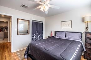 Farmington apartment for rent - the master bedroom has a large bed and a ceiling fan