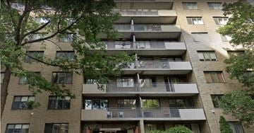 Montréal apartment for rent - A tall apartment building with balconies and trees in the foreground.